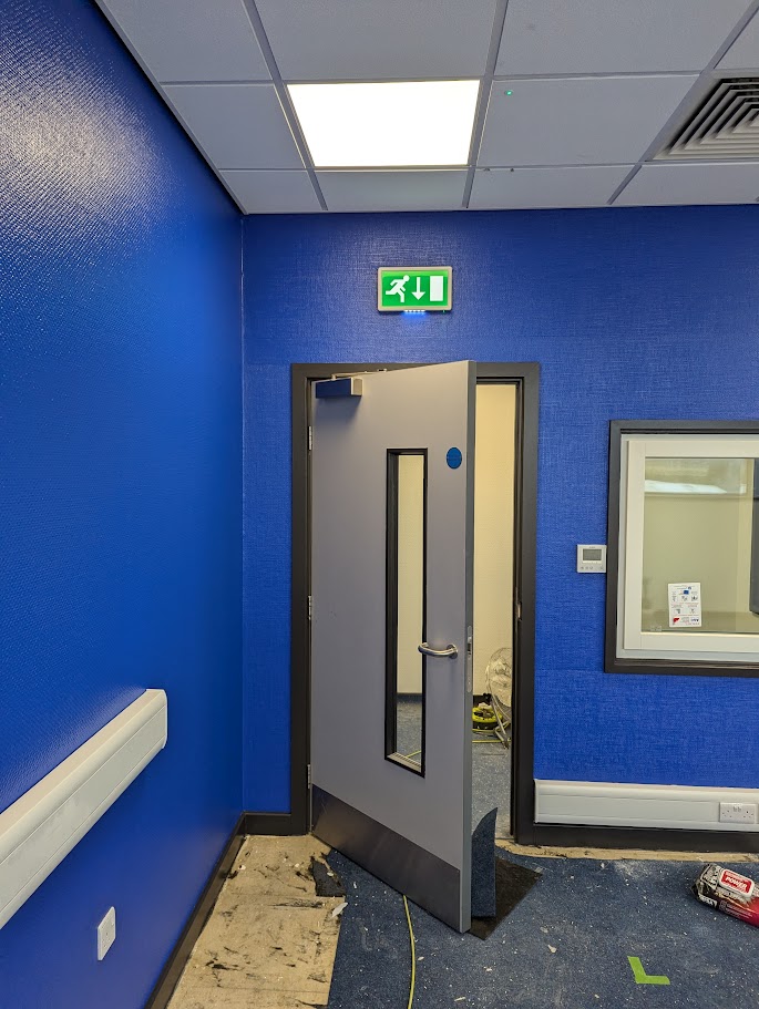 Commercial carpenters fitting a fire door set within an office refurbishment in Sheffield