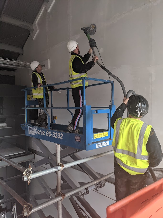 Contractors sanding a wall on a commercial project