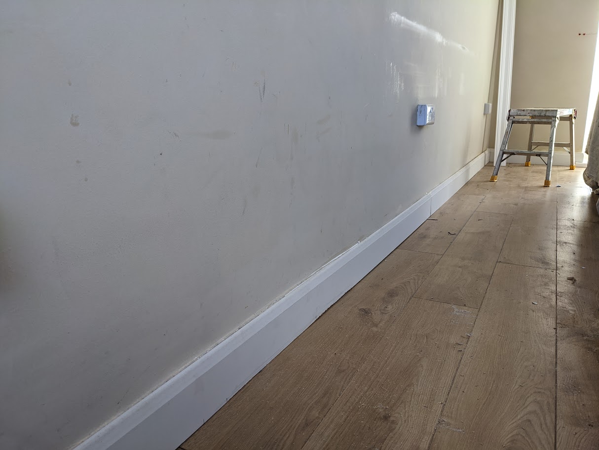 Commercial joinery team fitting skirting boards and architraves during finishing works