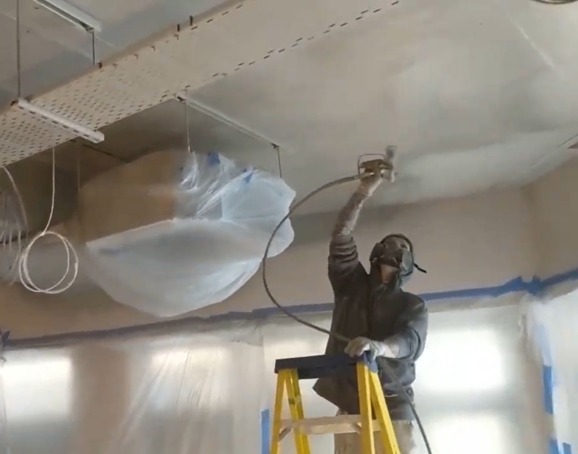 Spray painting ceilings in a large commercial space